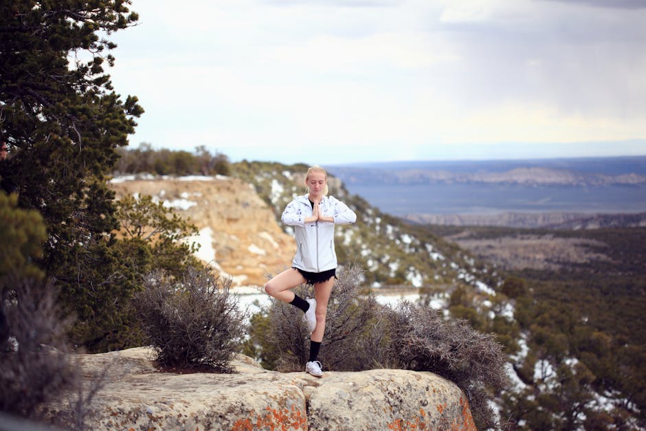 Woman practicing yoga on a cliff in Jensen, Utah with a serene mountain backdrop.